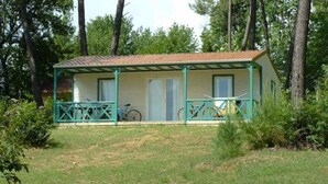 A small, single-story building with a porch and a covered area, surrounded by trees.