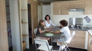 Een compacte keuken met moderne apparatuur, houten kastjes en een eethoek met stoelen.