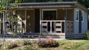 Een laag gebouw met een veranda, een zichtbare deur en een kleine tuin met struiken.