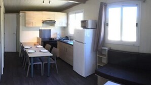 Een kleine keuken met een eettafel en stoelen, een koelkast en een magnetron.