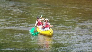 A yellow raft with three people paddling on a calm body of water. - ZEcamping 4 étoiles pataugeoire piscine chiens acceptés chalet TV 40m2 (Tamniès)