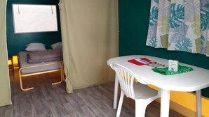 A room with a bed, a table with a red folder, and a curtain with a leaf pattern.