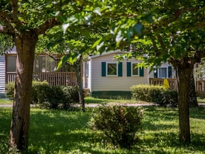 Une maison mobile dotée d’une cour clôturée, entourée d’arbres et d’herbe.