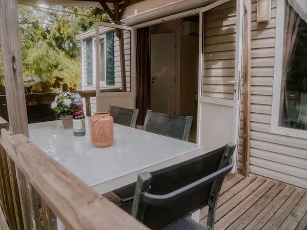 An outdoor dining area with a table and chairs, a lantern, and a wooden deck.