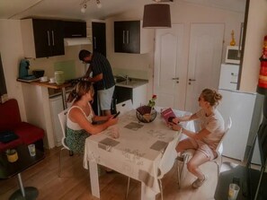 Una cocina compacta con electrodomésticos modernos, un comedor con una mesa para dos personas y un sofá rojo en la sala.