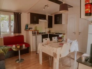 Un espacio habitable compacto con kitchenette, zona de comedor y un sofá rojo.