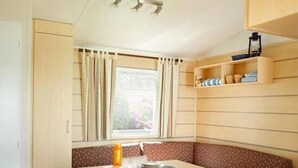 Cocina compacta con comedor, que incluye una mesa, sillas, un banco y una ventana con cortinas.