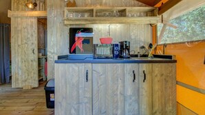 A rustic kitchen with wooden cabinets, a coffee machine, and a hanging light fixture.