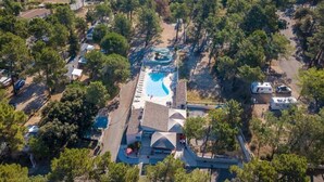 An aerial view of a resort with a swimming pool, RV parking, and a covered area with steps leading to a building.
