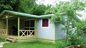 Une petite maison de campagne à un seul étage, dotée d’un porche couvert et d’un mur de soutènement en pierre.
