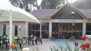 Un restaurant doté d’une terrasse, d’un toit recouvert de tuiles et de plantes en pot.