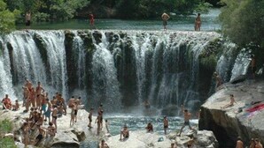 Une cascade où des personnes se baignent et profitent de l'eau.