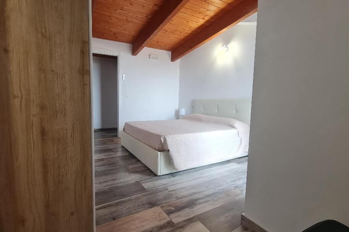 Une chambre à coucher avec un lit, un plancher en bois et un mur blanc.