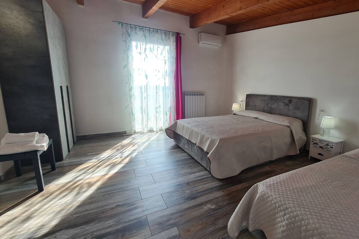 Une chambre avec deux lits, une table de chevet, une lampe et un radiateur.