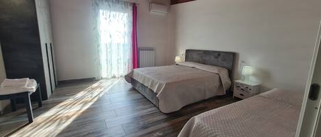 Un dormitorio con dos camas, una mesita de noche, una lámpara y un radiador.
