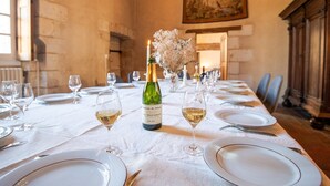 A long dining table set with white plates, wine glasses, and a bottle of Châteauneuf du Pape wine. - 16th century hunting lodge - Château de Nitray (Athée-sur-Cher)