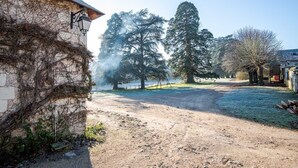 A rural setting with a dirt path, a building with vines, and large trees. - 16th century hunting lodge - Château de Nitray (Athée-sur-Cher)
