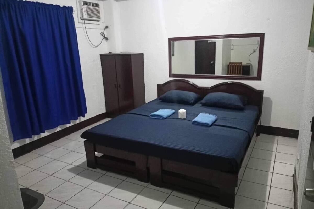 A room with a bed, a wardrobe, a mirror, and a curtain.