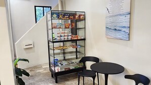 A reception area with a marble floor, a glass display case with snacks, two black chairs, and a poster on the wall. - Pension Bacolod (Bacolod)