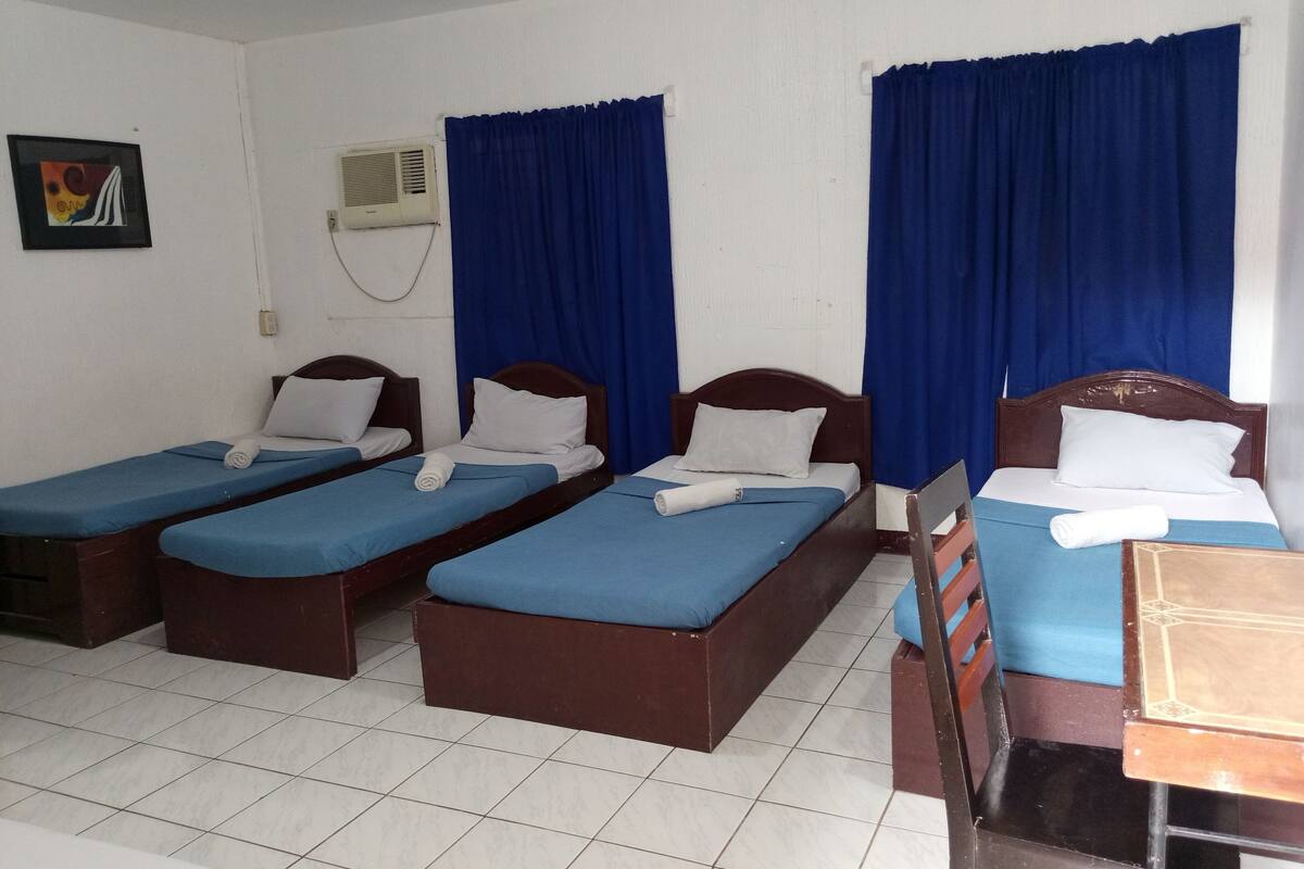 A hotel room with two single beds, a wooden desk, and a chair.