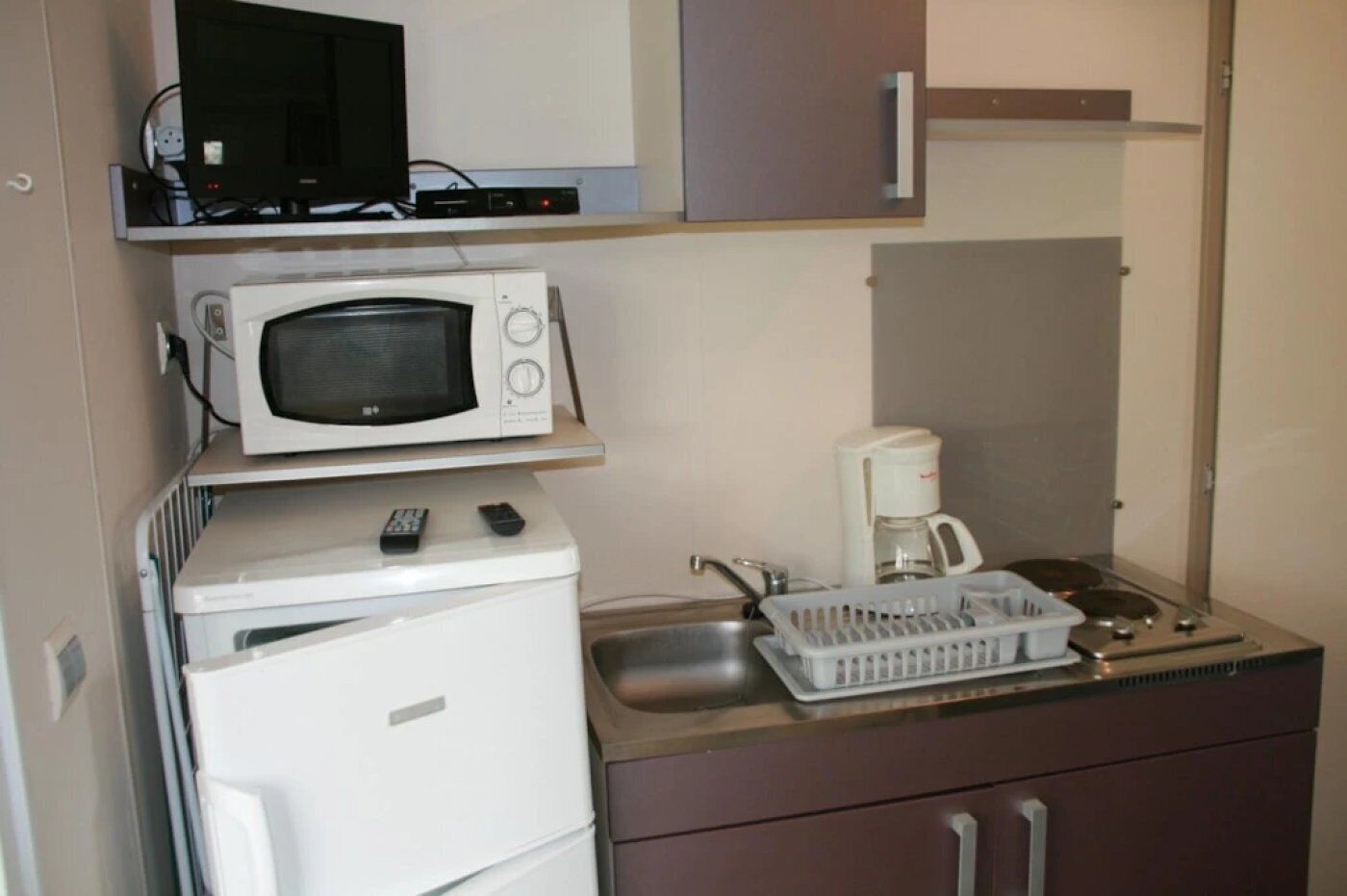 A compact kitchenette with a microwave, coffee maker, and a small refrigerator.