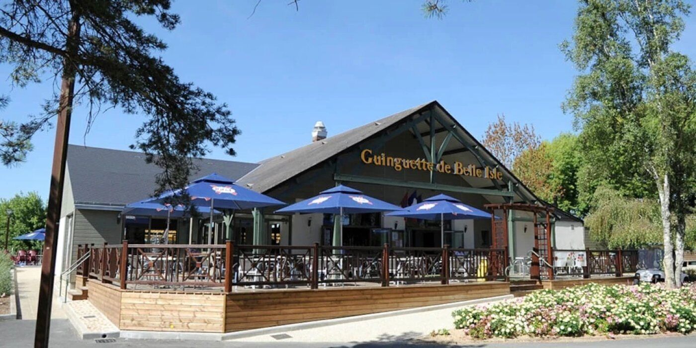 A restaurant with outdoor seating and blue umbrellas.