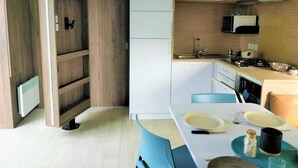 Una cocina moderna con armarios blancos, un microondas integrado y un comedor con mesa y sillas.
