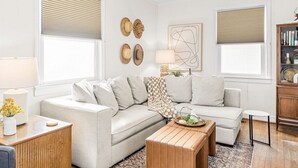 A living room with two sofas, a coffee table, a lamp, and a bookshelf. - Walk to Sound + Dining | Fenced Yard | Extended Stays Welcome Pet Friendly (Morehead City)