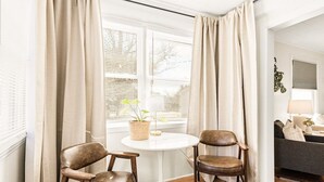 A room with two leather chairs, a white round table, a potted plant, and a sofa in the background. - Walk to Sound + Dining | Fenced Yard | Extended Stays Welcome Pet Friendly (Morehead City)