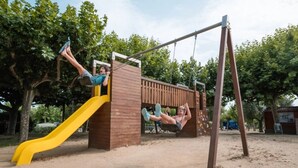 Un parque infantil con un tobogán amarillo y columpios.