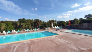 Zona de piscina con múltiples sillas de descanso y una piscina separada.