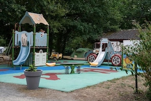 A playground with a slide, climbing structures, and a seesaw.