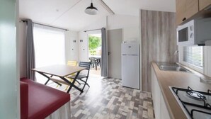 Una cocina moderna con estufa a gas, refrigerador y una zona de comedor con mesa y sillas.