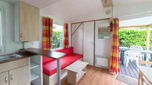 Cocina compacta con comedor, un banco rojo y vistas al exterior.
