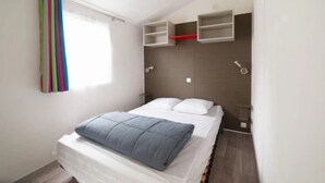 A bedroom with a bed, a window with curtains, and built-in shelves.