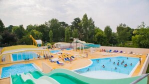 A water park with multiple pools and slides, surrounded by trees.