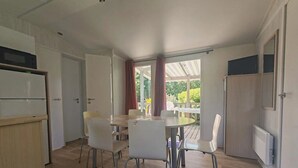 Eine moderne Küche mit weißen Schränken, einer eingebauten Mikrowelle und einem Essbereich mit einem runden Tisch und weißen Stühlen.