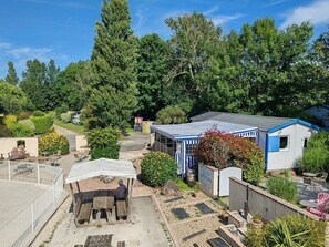 Een woonhuis met een omheinde achtertuin, een overdekt zitgedeelte en een kleine schuur.