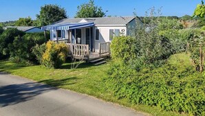 Ein Bungalow mit Veranda, umgeben von viel Grün.