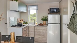 Eine kleine Küche mit Herd, Mikrowelle, Spüle und Kühlschrank.