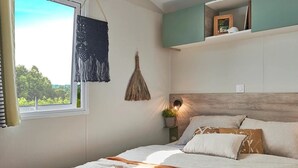 Ein Schlafzimmer mit einem Bett, einem Fenster, einer Wandlampe und einem Wandbehang aus Makramee.