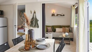 Ein modernes Interieur mit Essbereich, einer Sofagruppe und Blick durch ein großes Fenster.