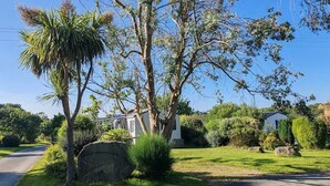 Un barrio residencial con un camino pavimentado, un muro de piedra y una casa con un césped cuidado.
