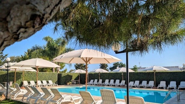 En swimmingpool med liggestole og parasoller.