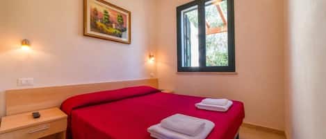 A hotel room with two beds, a window with a view, a painting on the wall, and bedside lamps.