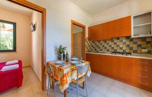A compact kitchen with wooden cabinets, a tiled backsplash, and a dining area with a table set for two. - ZEcamping 3* pataugeoire bien-être locatif TV BBQ clim 30m2 4 pers (Marsala)
