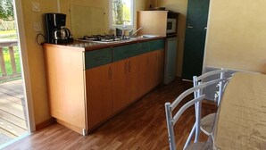 Una cocina compacta con armarios de madera, estufa a gas, cafetera y microondas.