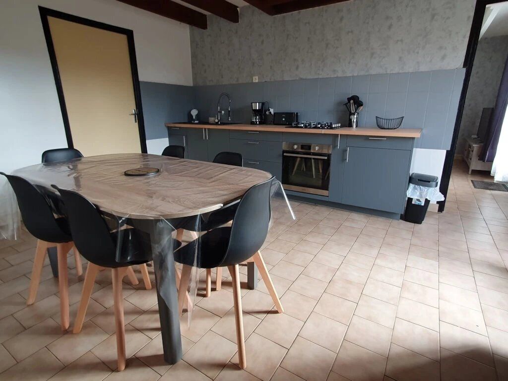 Uma cozinha moderna com uma mesa de jantar redonda e cadeiras, forno embutido e cafeteira.