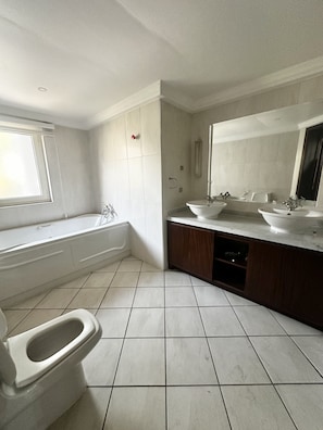 Une salle de bain moderne avec une baignoire, deux lavabos et des toilettes.