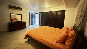 Een slaapkamer met een bed, een dressoir en een kledingkast.